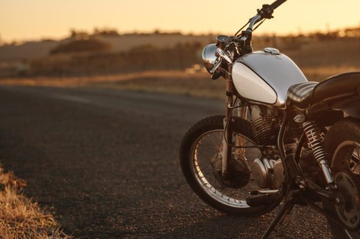 Vintage standard motorcycle parked on a country road at golden hour