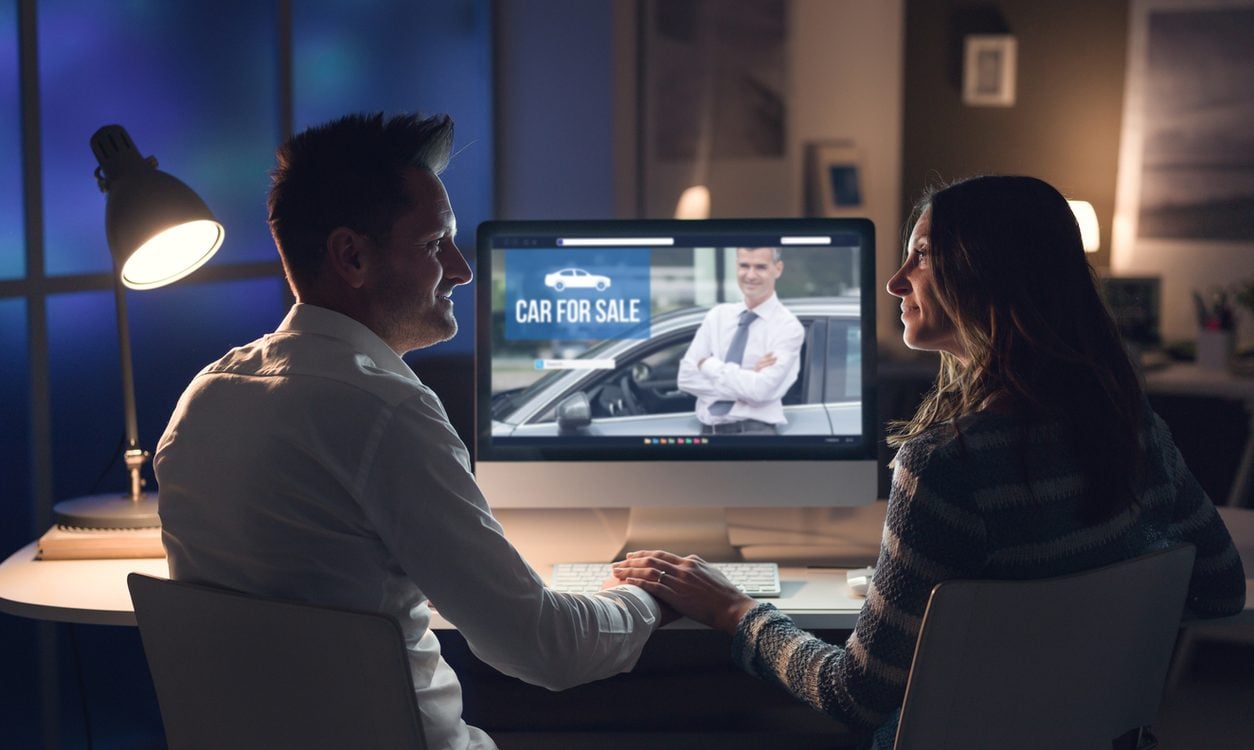 Couple looking at a car for sale listing on a computer at home
