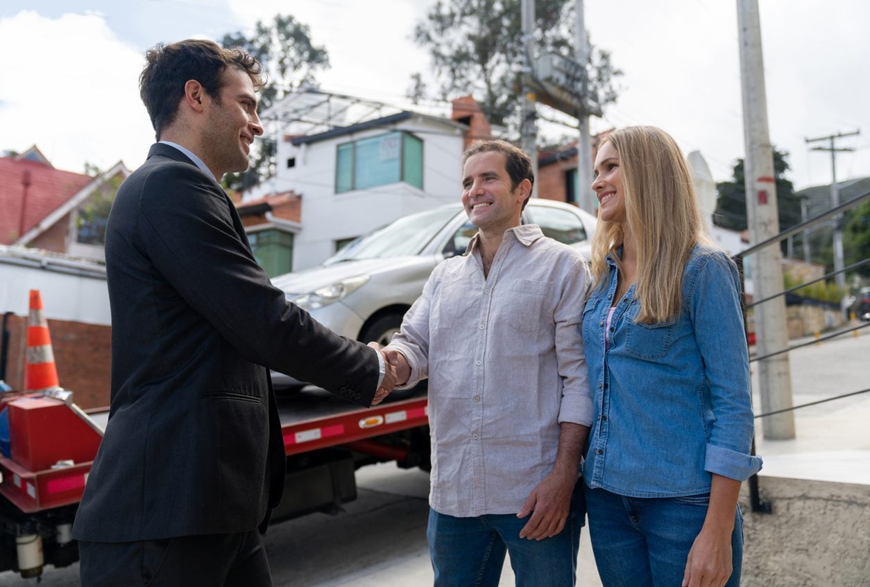 Couple greeting a driver as a car is delivered to their home