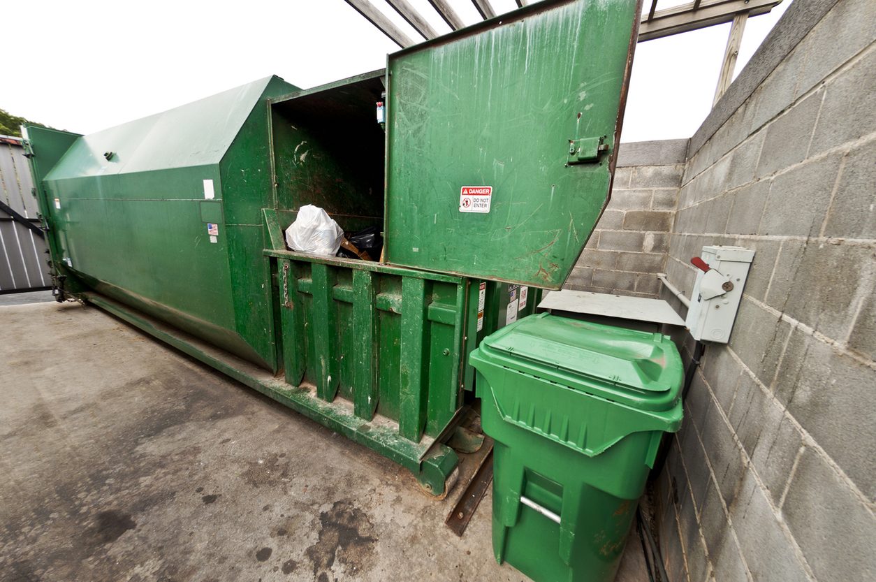 Commercial waste compactor container beside a building