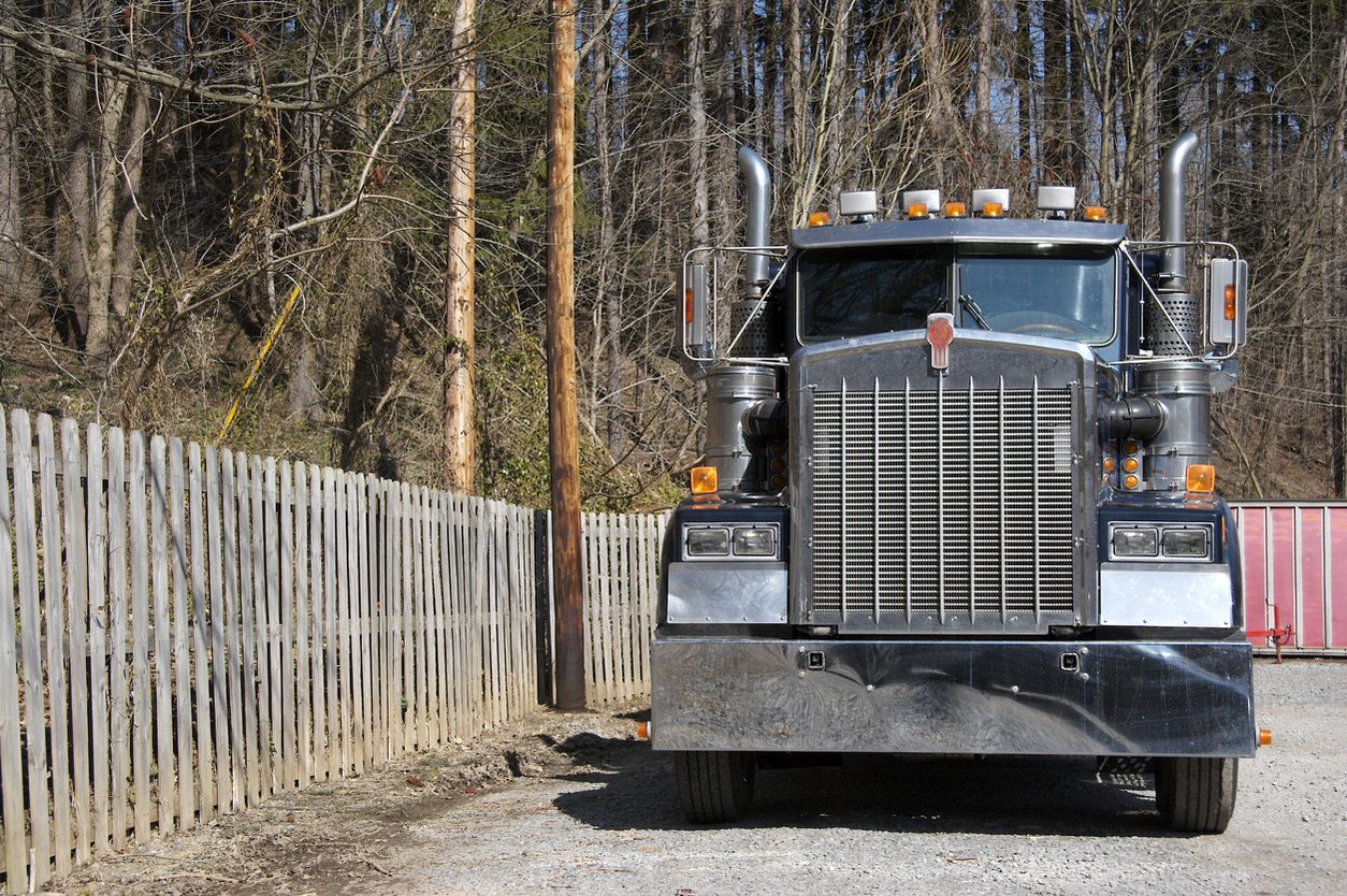 Front view of a conventional tractor parked by a fence