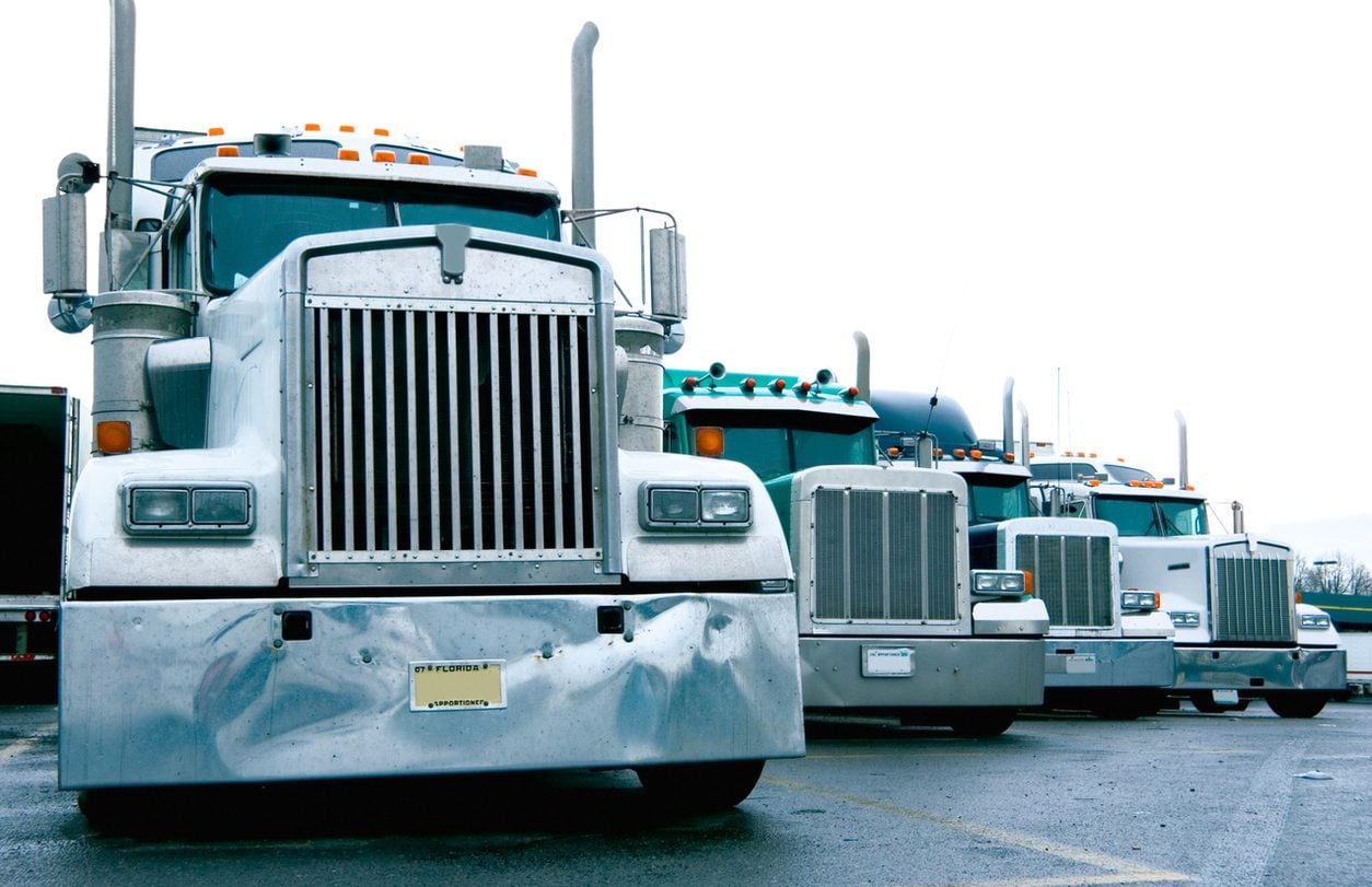 Row of conventional tractors parked nose out at a truck stop