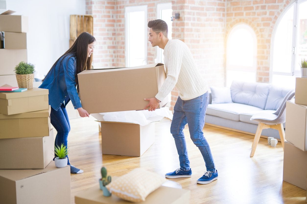 Couple carrying boxes into a new home