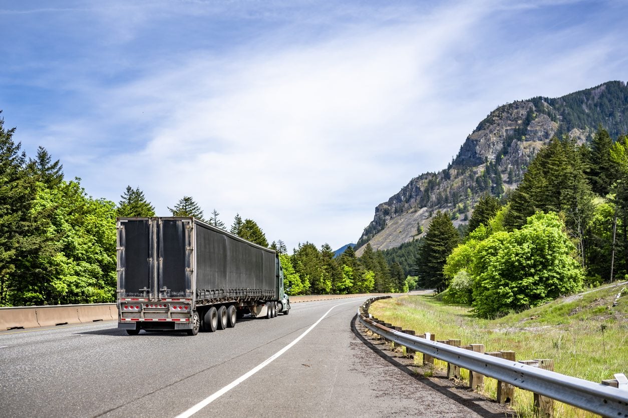 Semi truck with a covered load on a mountain road