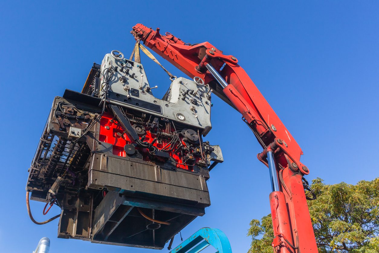 Crane lifting a heavy machine by its rigging points