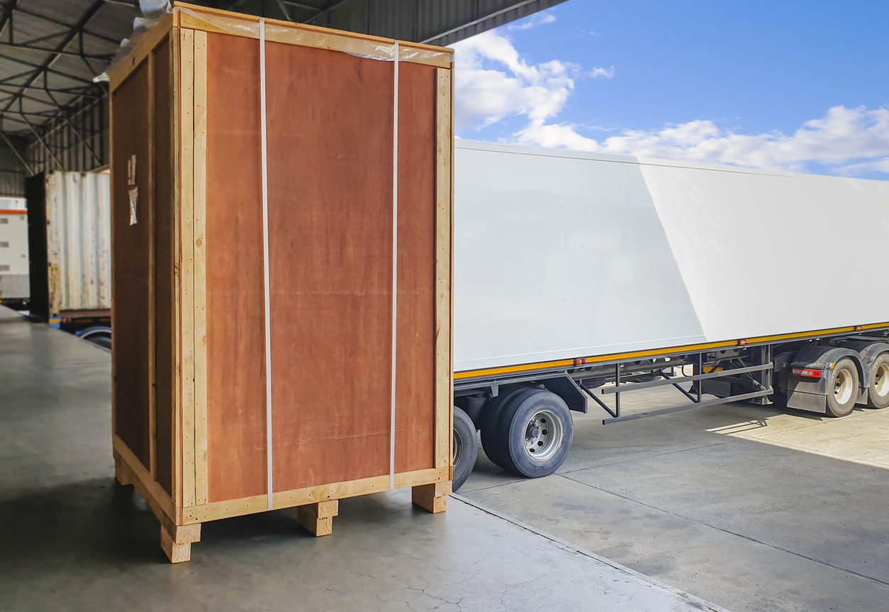 Large wooden crate on a pallet beside a trailer at a dock