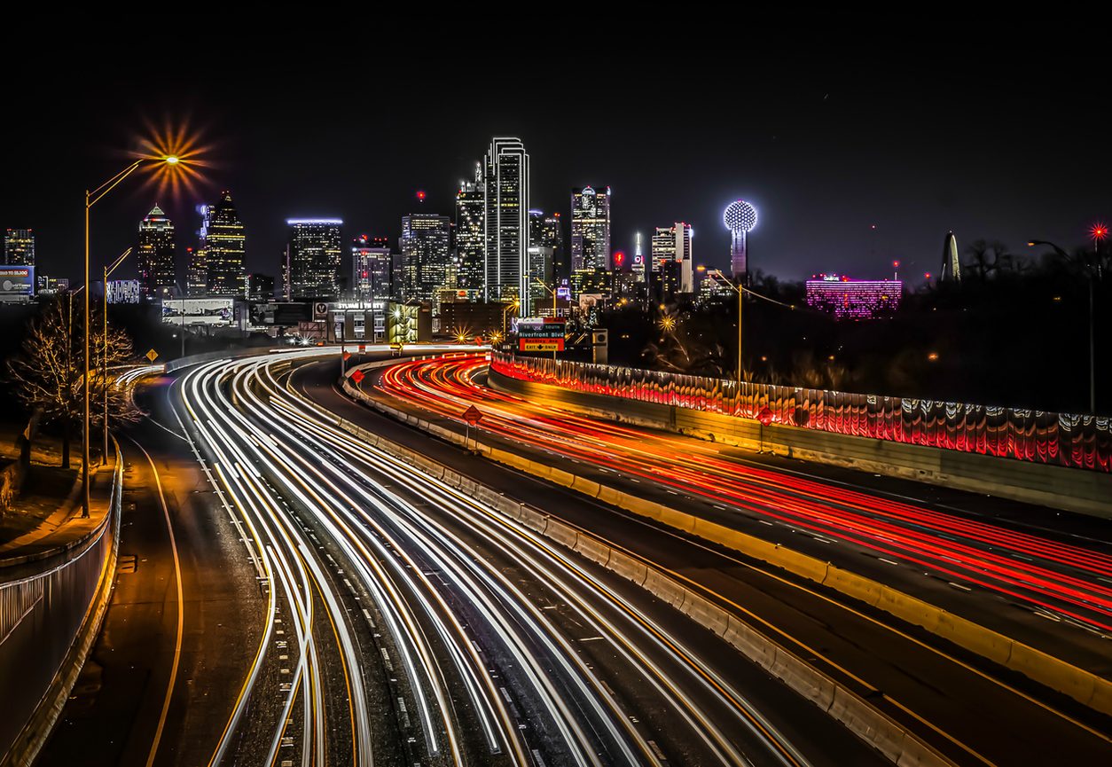 Long exposure of freeway traffic light trails below a city skyline at night