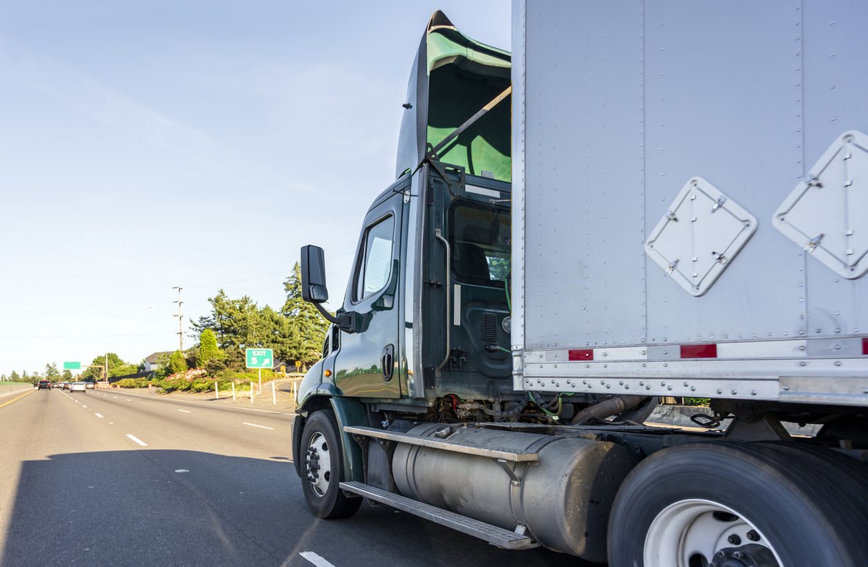 Day cab tractor with a box trailer on a highway