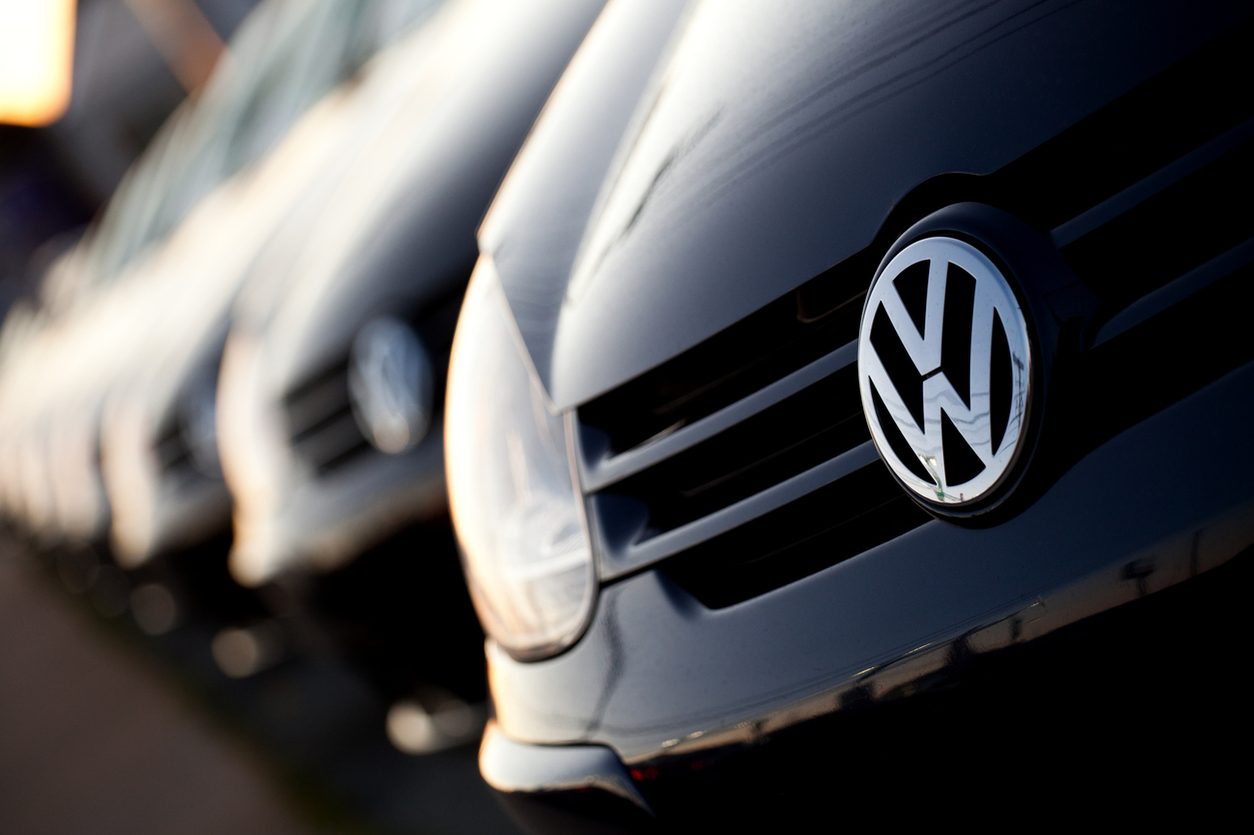 Row of new cars parked side by side on a dealership lot