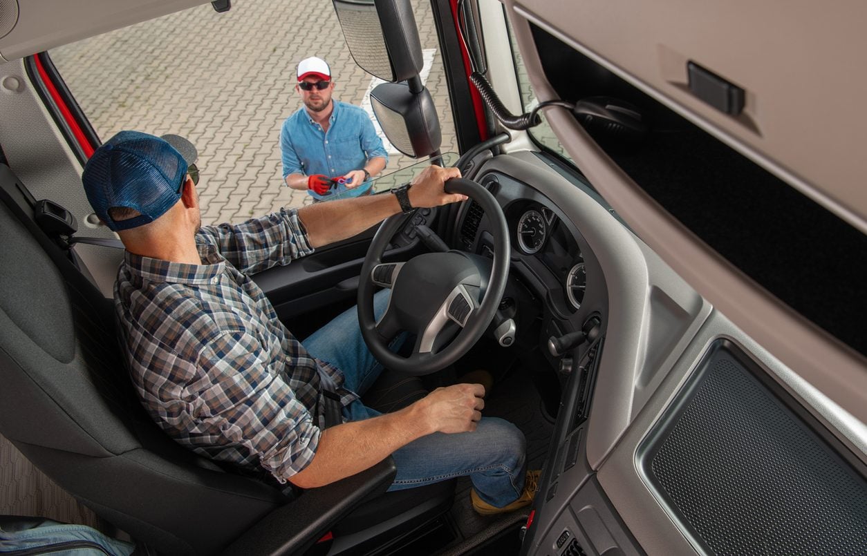 Dispatcher handing paperwork to a driver in the cab