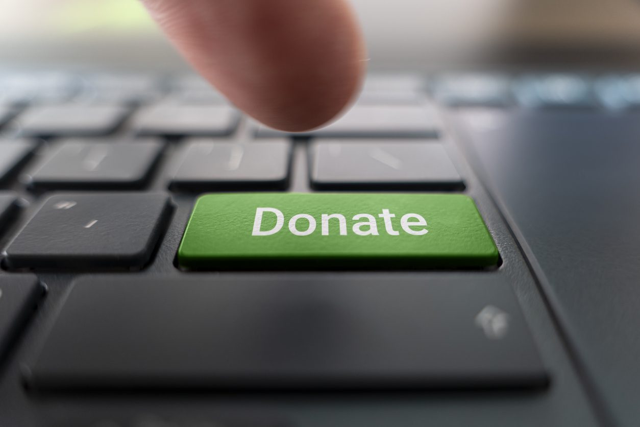 Finger pressing a donate key on a keyboard