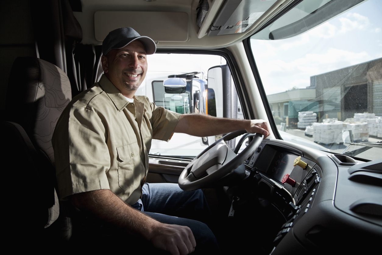 Driver seated at the wheel inside a tractor cab