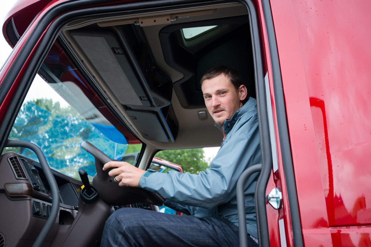 Driver seated in a truck cab at the dashboard