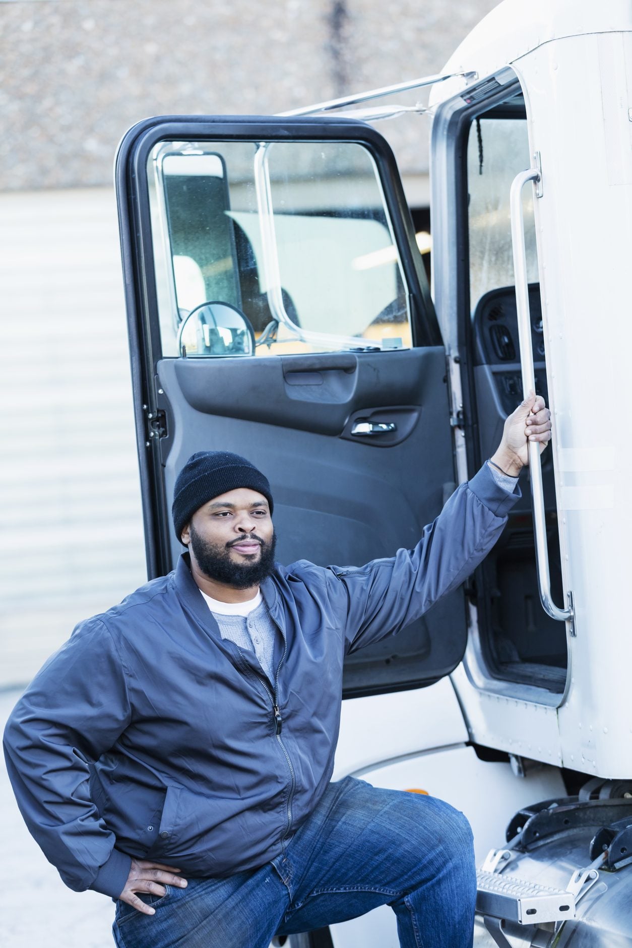 Driver standing in the open doorway of a tractor cab