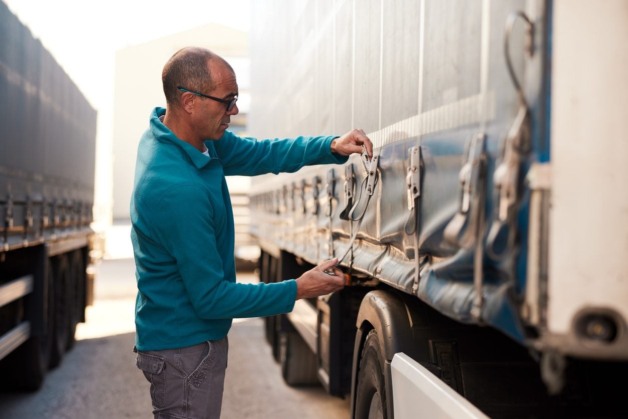 Driver adjusting ratchet tie down straps on a trailer