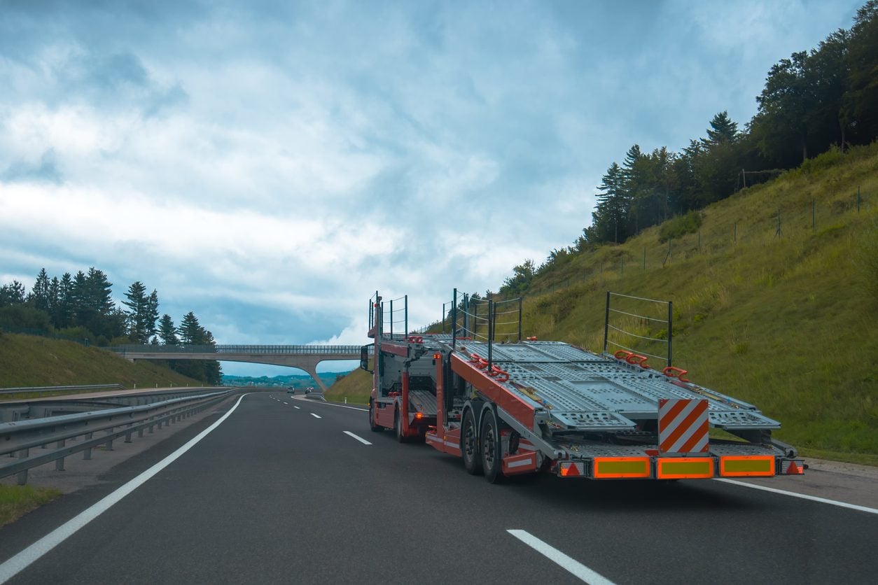 Semi truck with an empty car carrier trailer on a highway