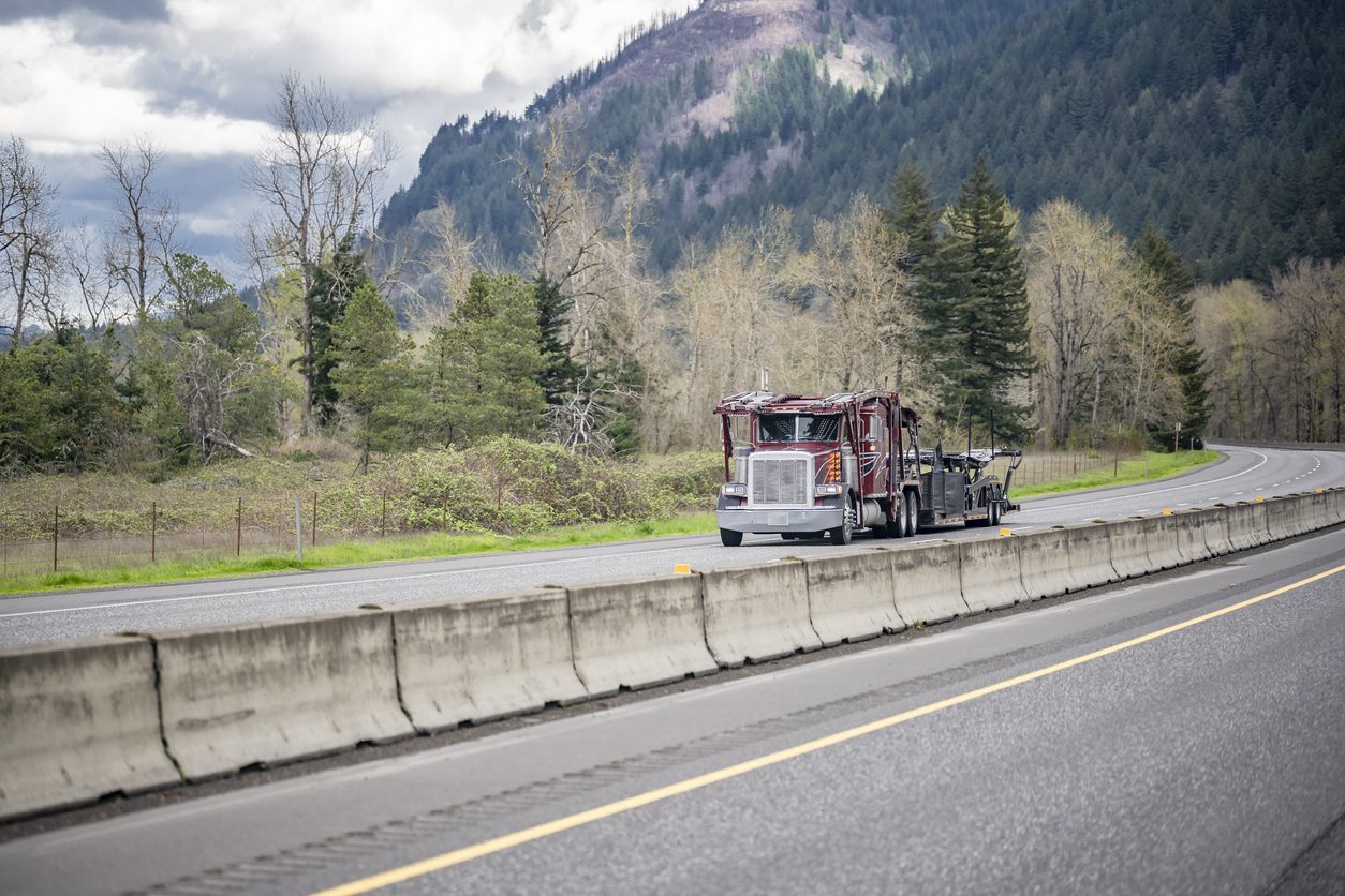 Car hauler with an empty trailer on a mountain highway