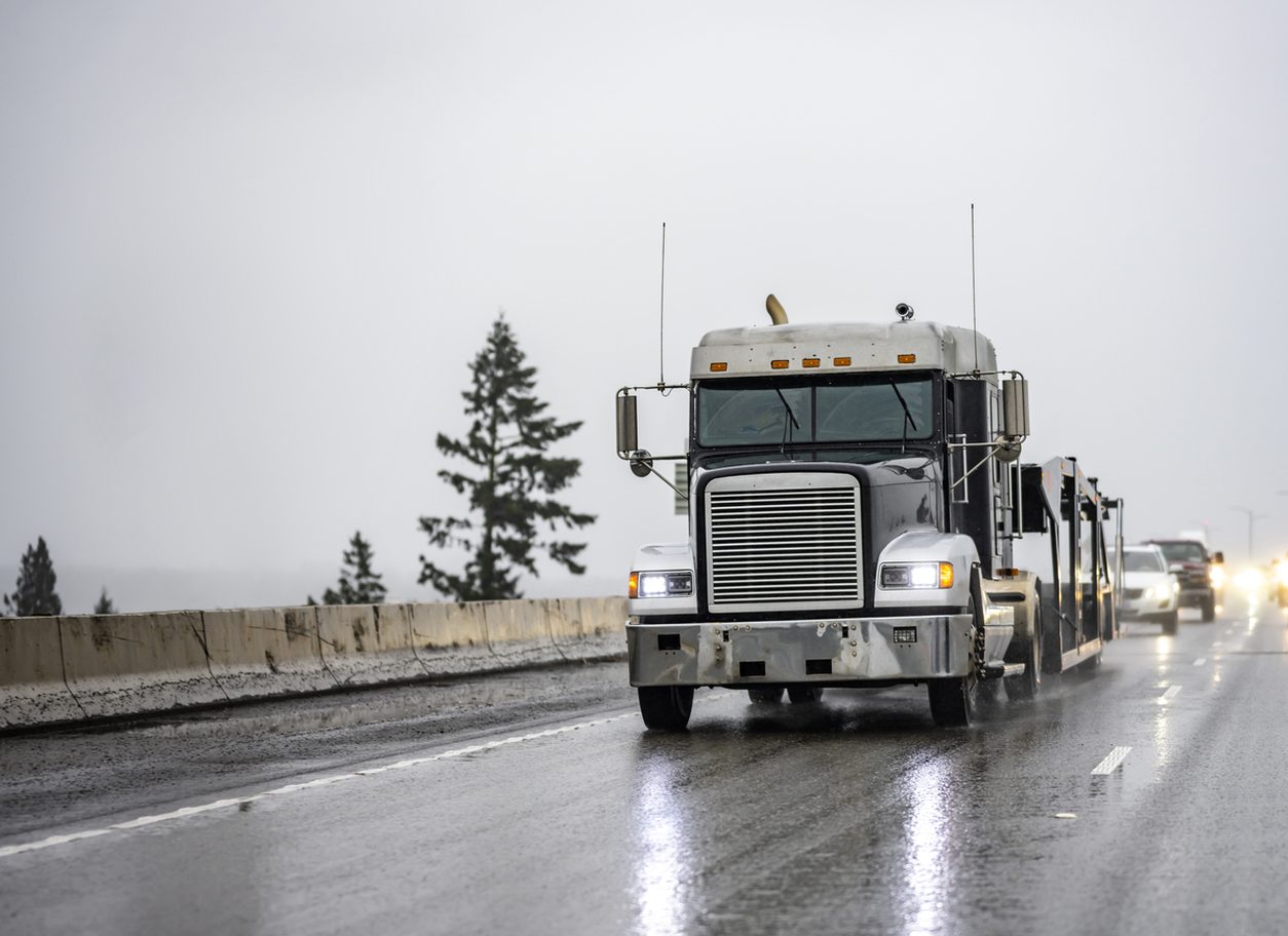 Car hauler running empty on a wet highway