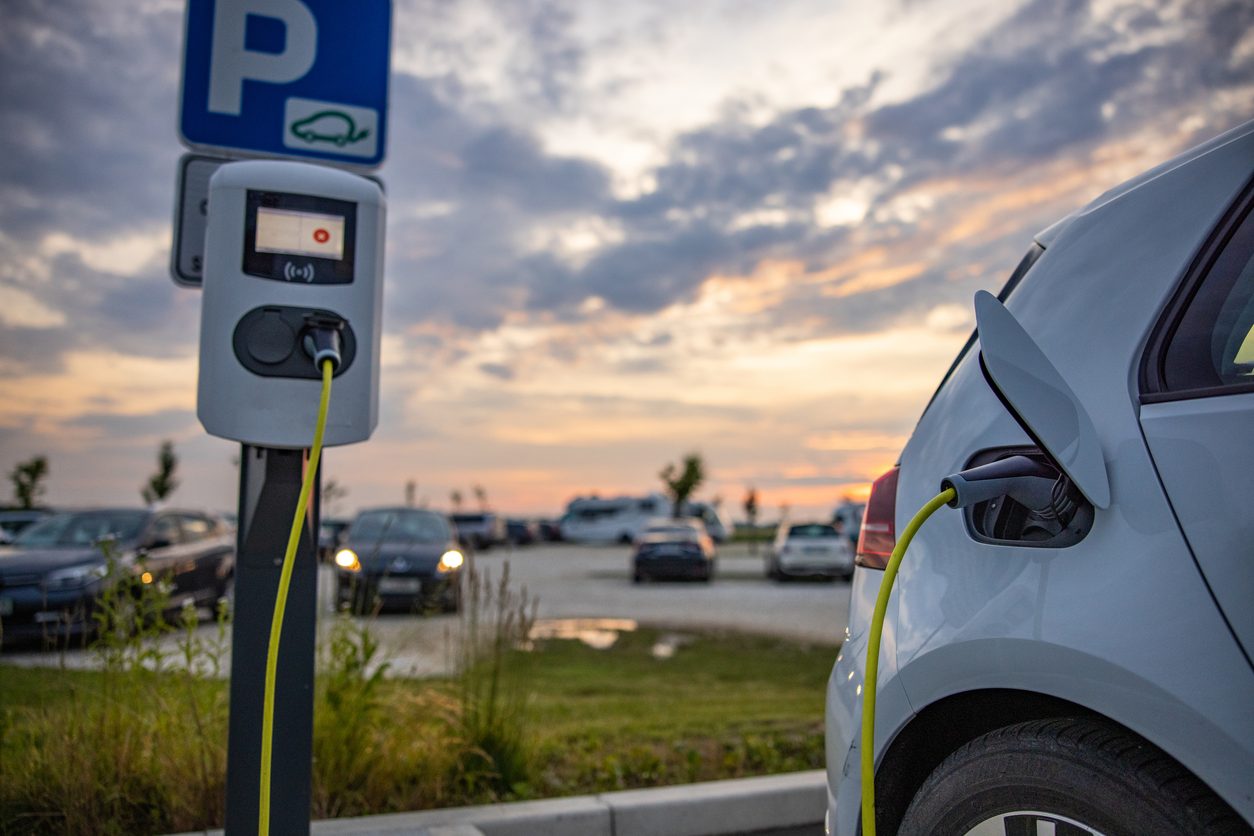 Electric car plugged in at a parking lot at dusk