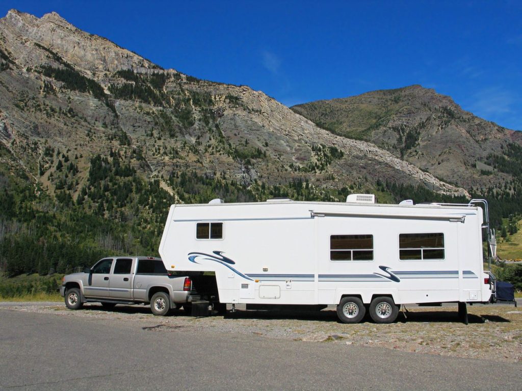 Fifth wheel trailer hitched to a pickup on a mountain road