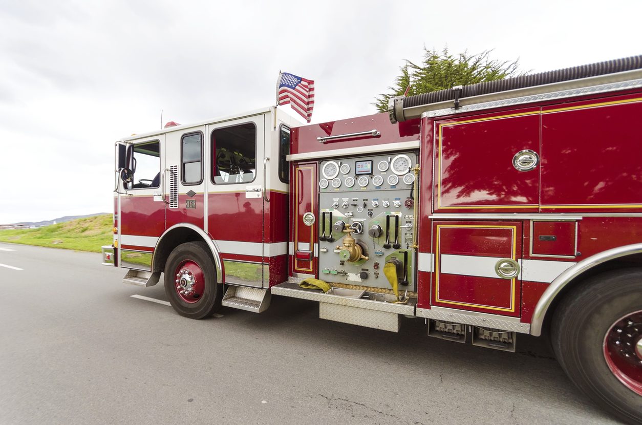 Fire engine with its pump panel visible traveling a highway
