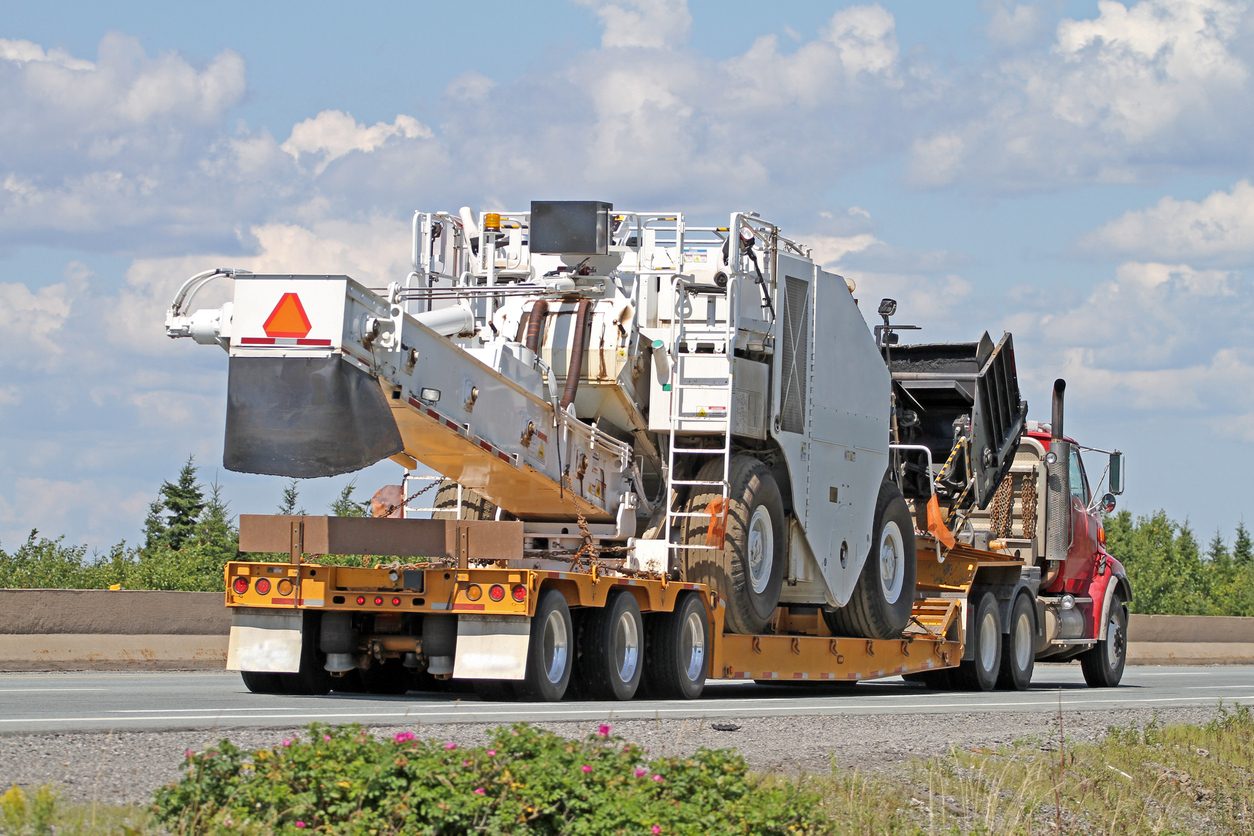 Flatbed semi hauling a road milling machine
