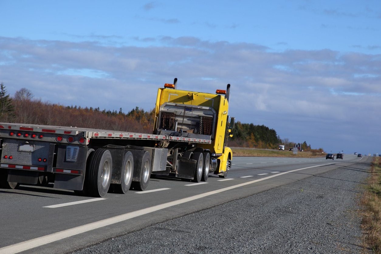 Semi truck hauling a flatbed trailer on a highway