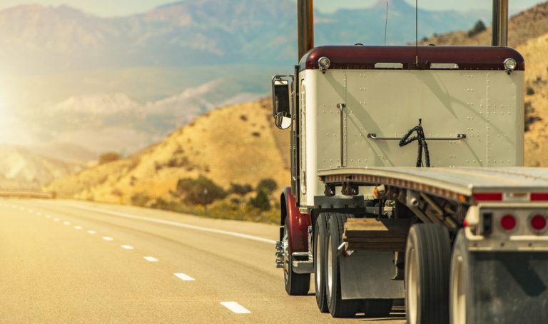 Semi truck with a flatbed trailer on a scenic Utah road