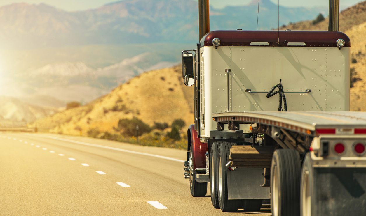 Semi truck with a flatbed trailer on a scenic Utah road