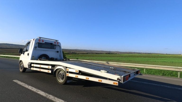 Flatbed tow truck with its deck tilted down at the roadside