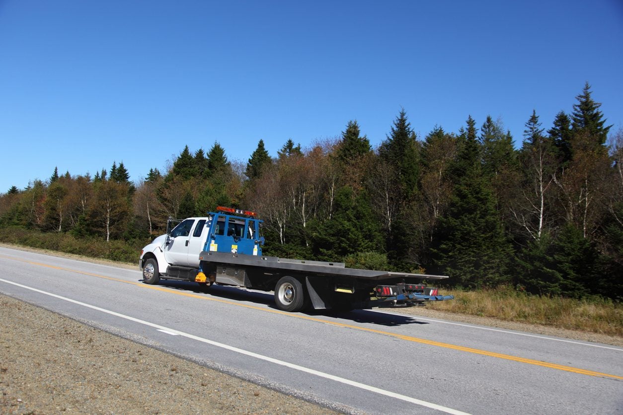 Flatbed tow truck parked beside a highway
