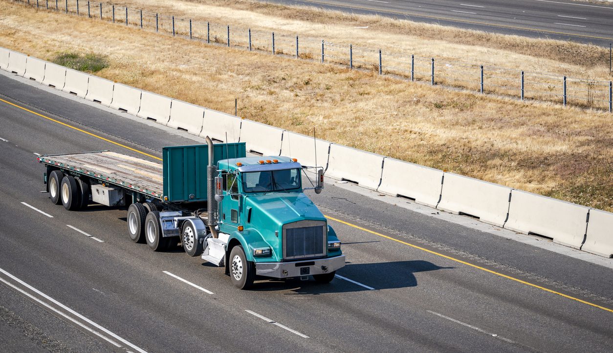 Conventional tractor with an empty flatbed on a highway