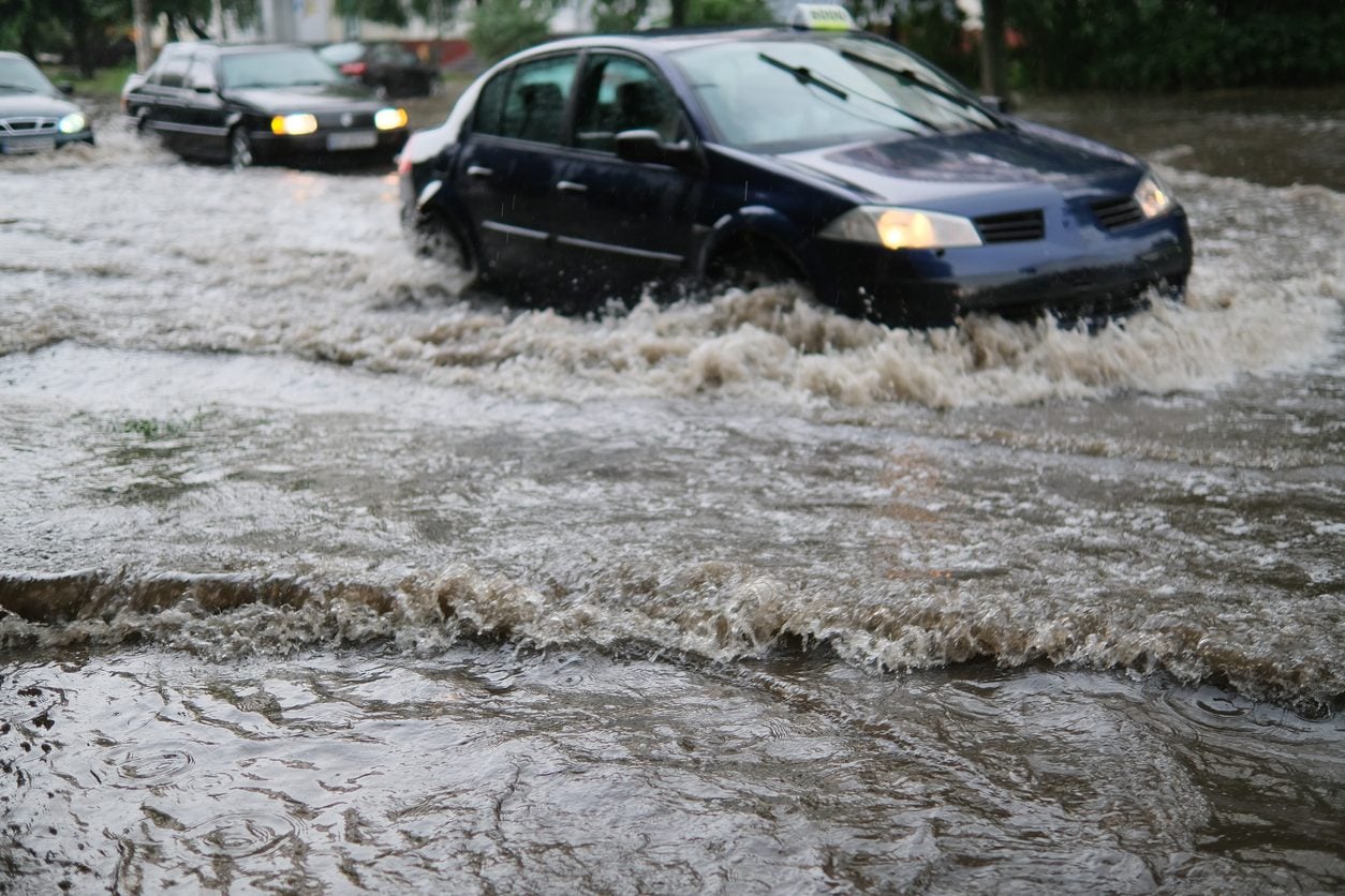 Cars driving through a flooded street in heavy rain