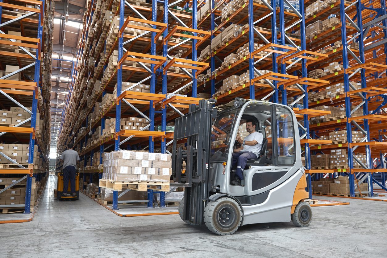 Forklift working between racked pallets in a warehouse