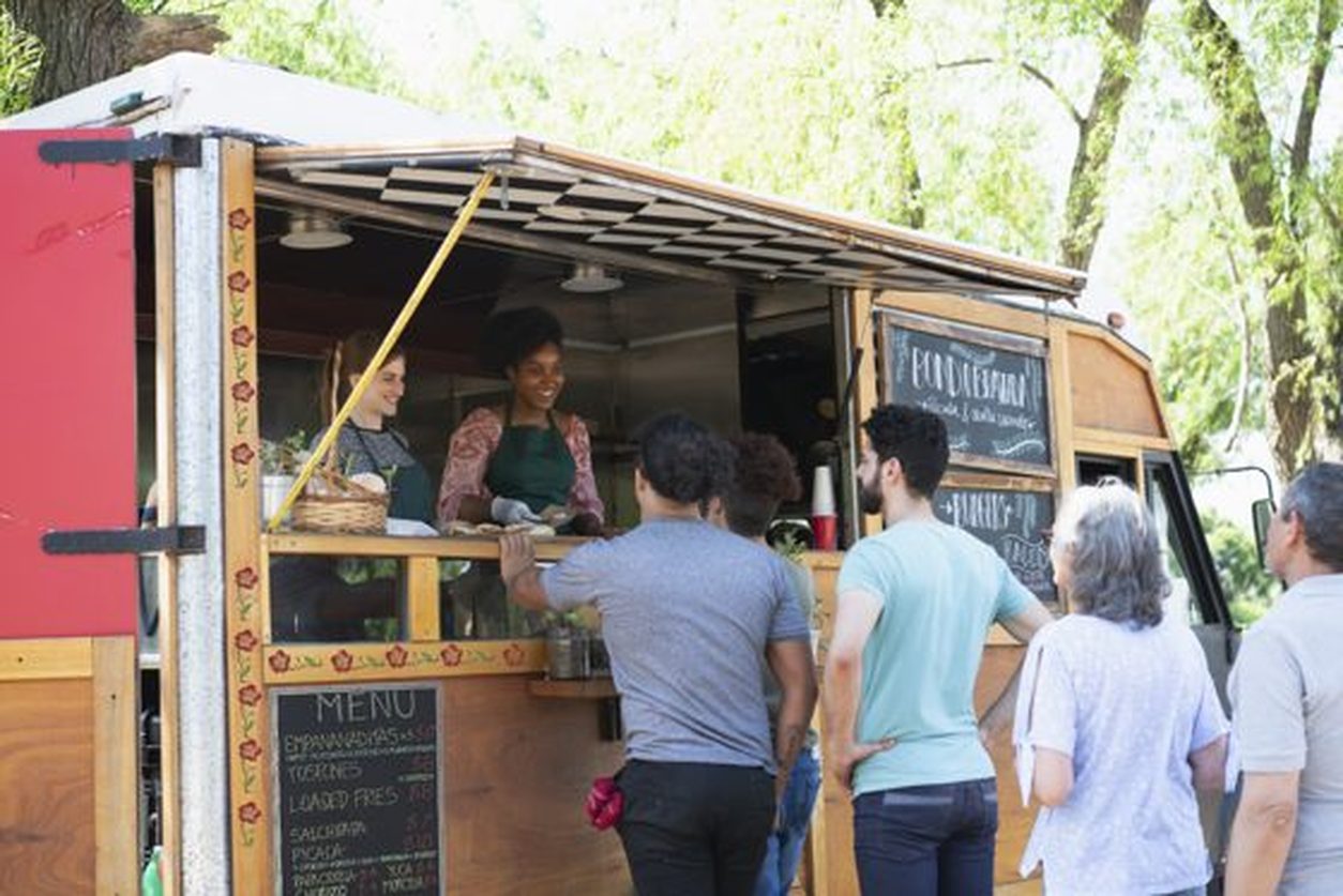 Customers lined up at the service window of a wooden food truck