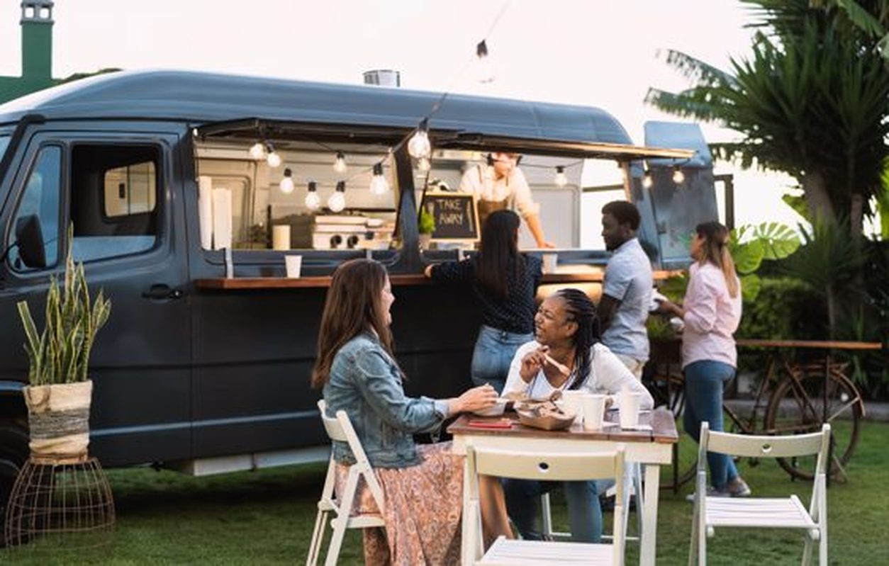 Modern black food truck serving diners at outdoor tables