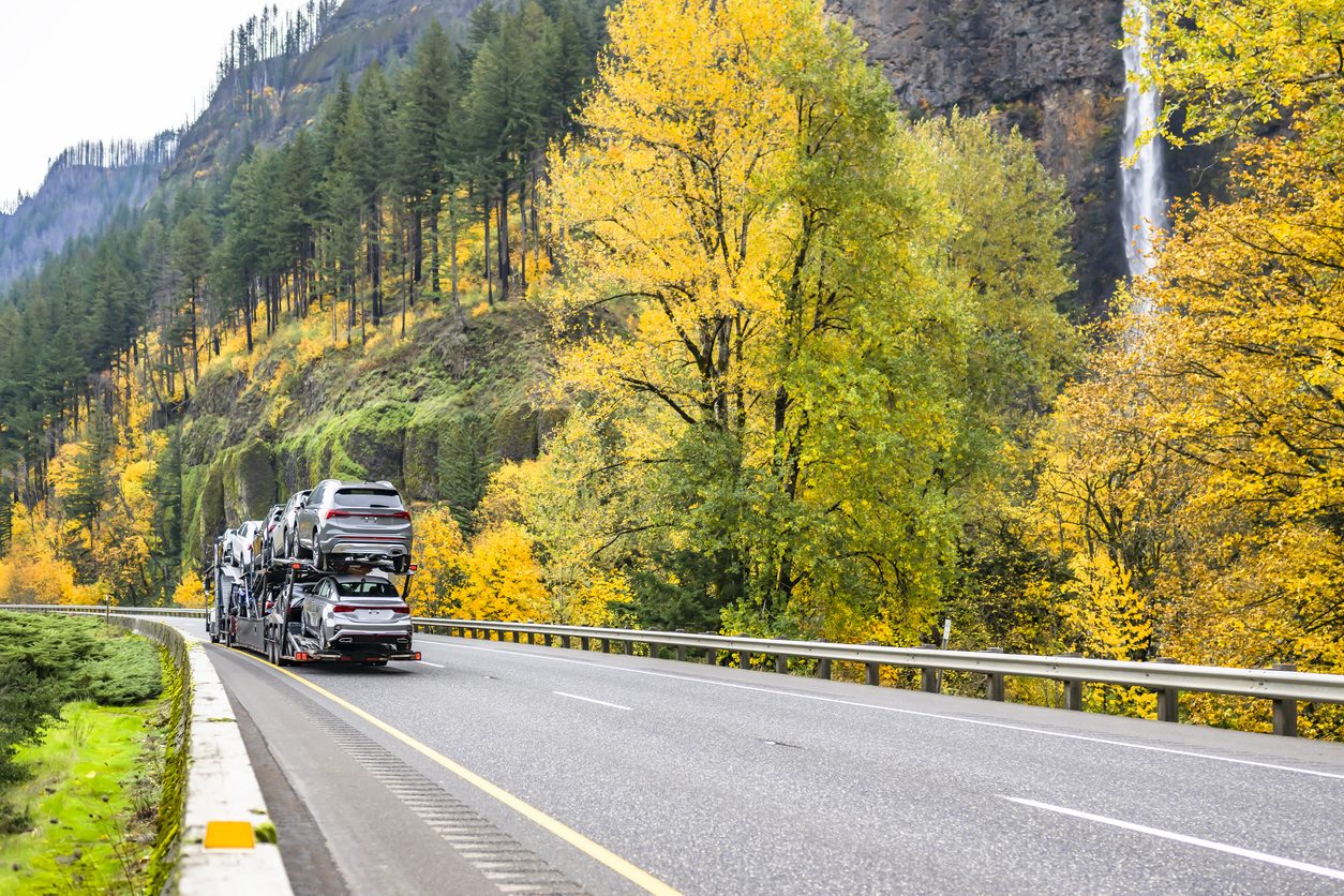Car hauler on a winding highway through an autumn canyon
