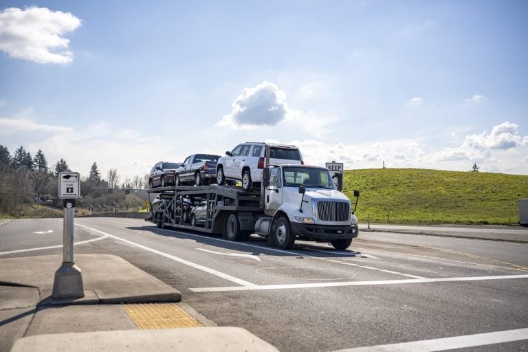 Loaded car hauler waiting at a city intersection