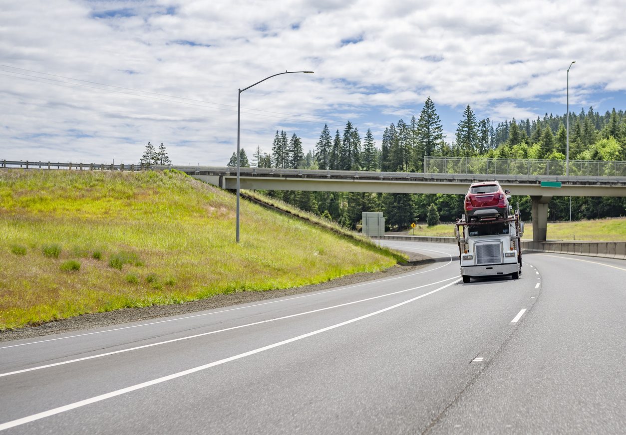 Loaded car hauler on a highway through forest