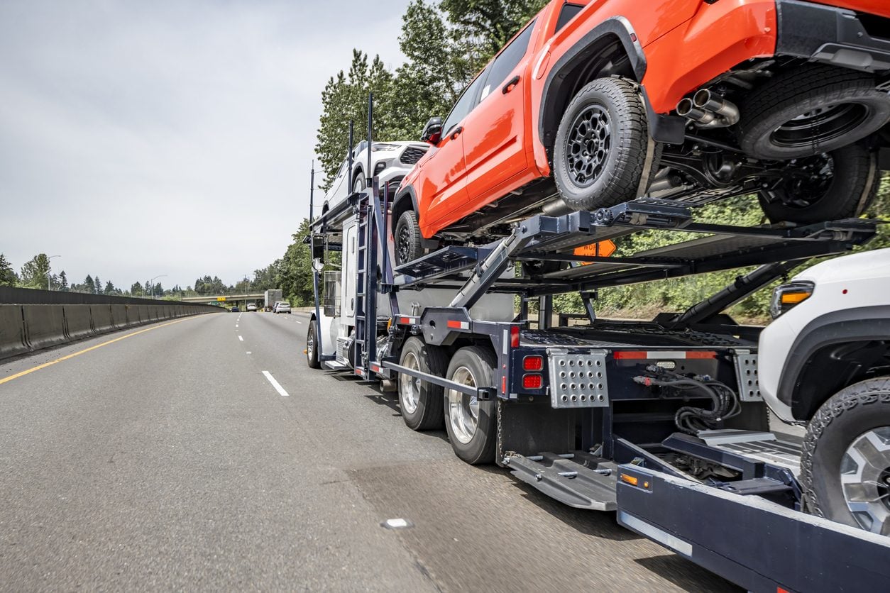 Car hauler carrying a pickup truck on the upper deck
