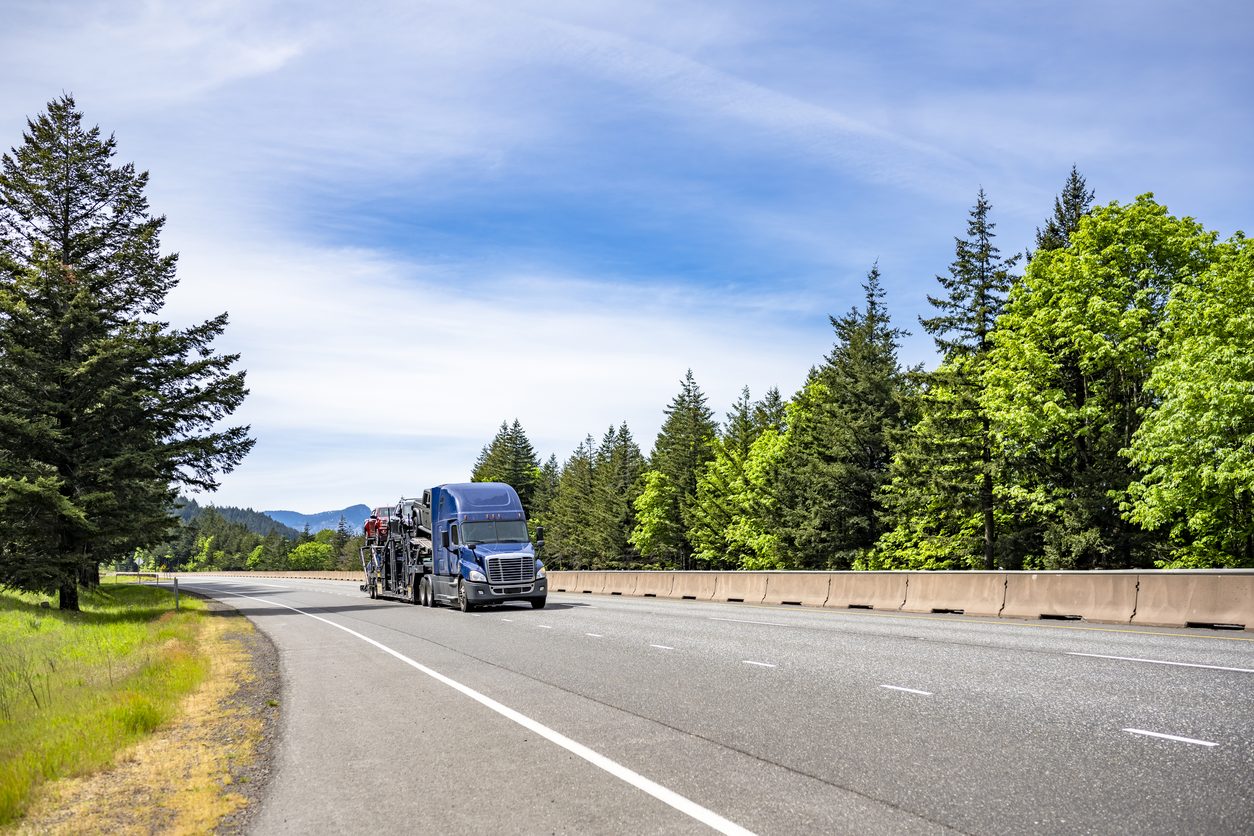 Car hauler on a pine lined highway
