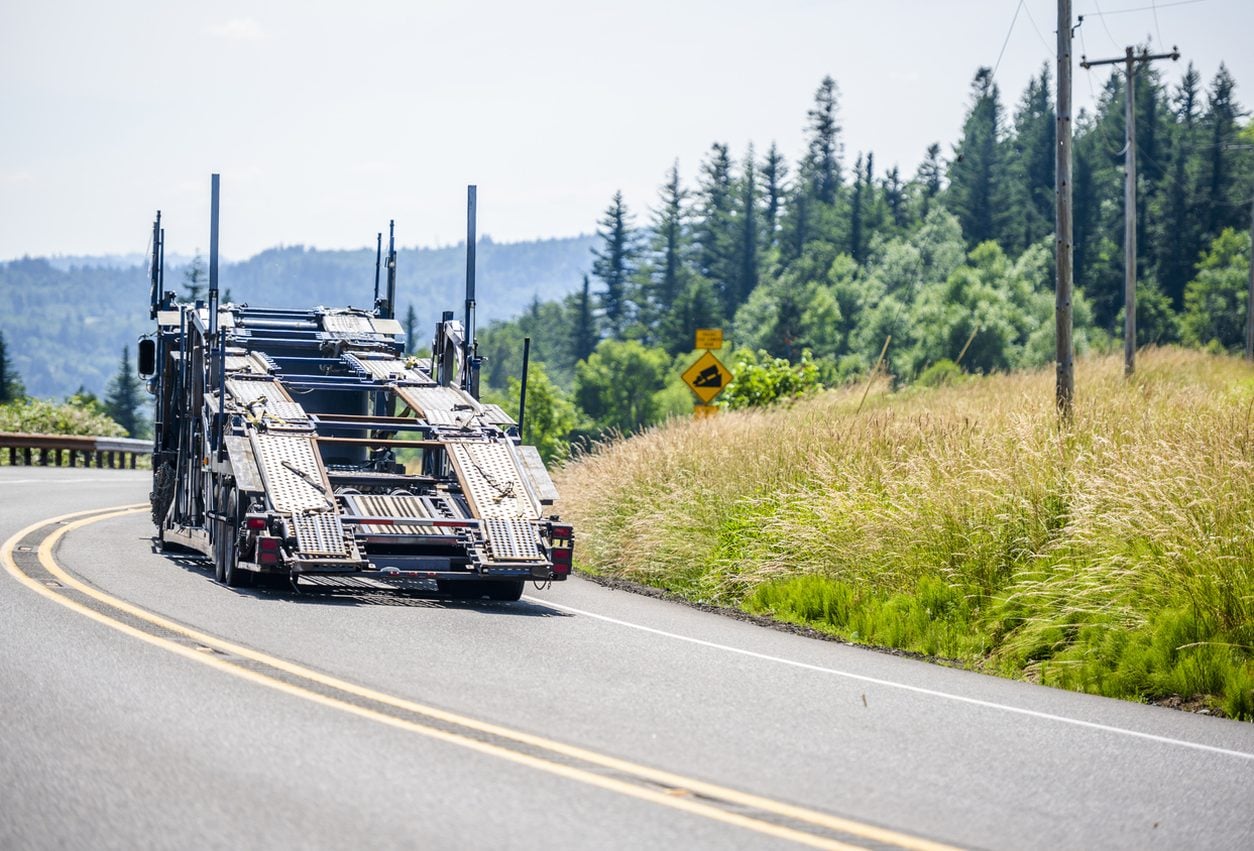 Car hauler running a rural highway toward a pickup