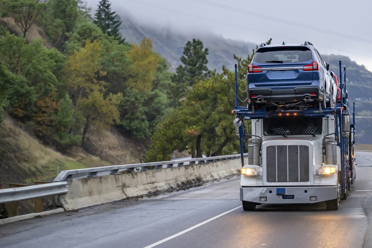 Car hauler with headlights on approaching on a two lane road
