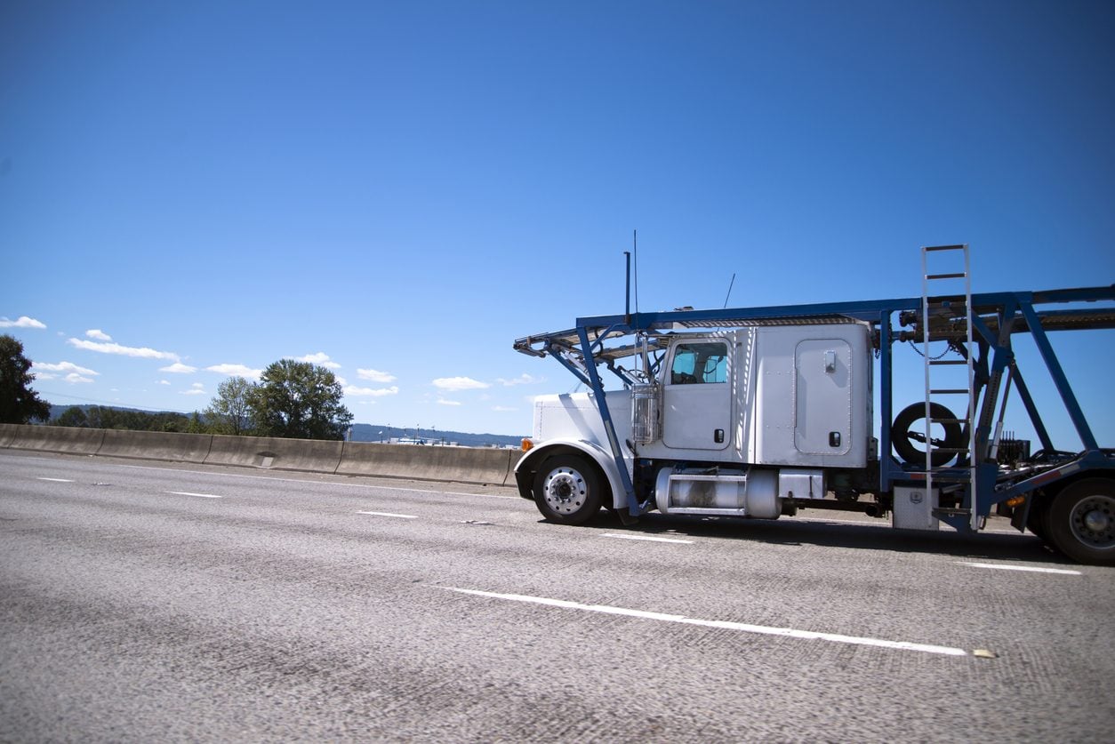 Car hauler running a wide highway toward a pickup