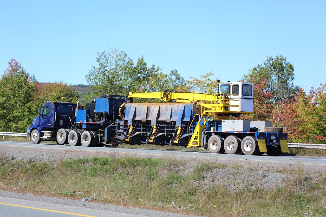 Conventional tractor hauling large yellow industrial equipment