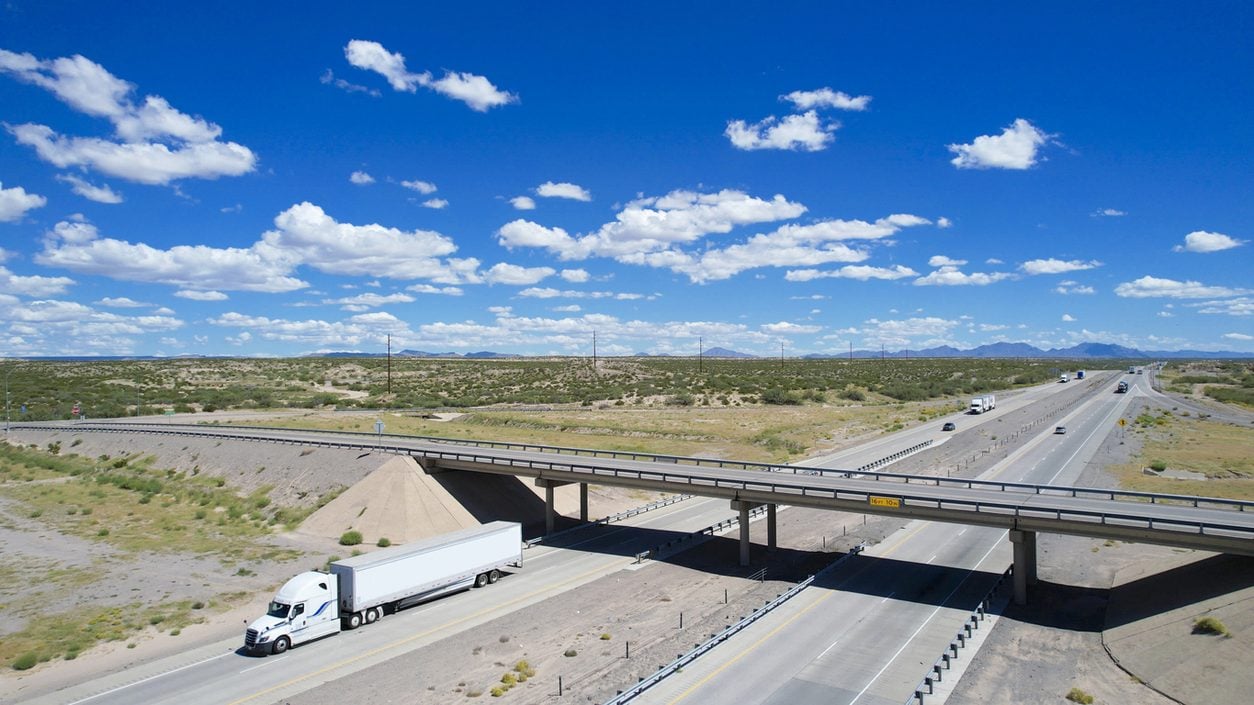 Aerial view of a white semi truck on an interstate overpass in Texas