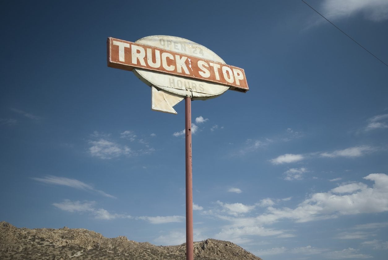 Weathered truck stop sign against a blue sky