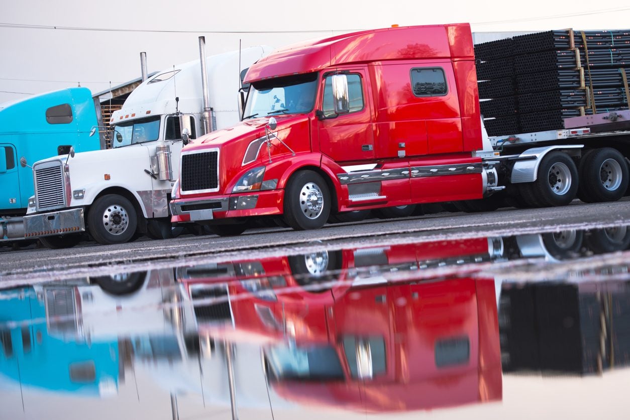 Tractor units and a flatbed trailer at a parking lot