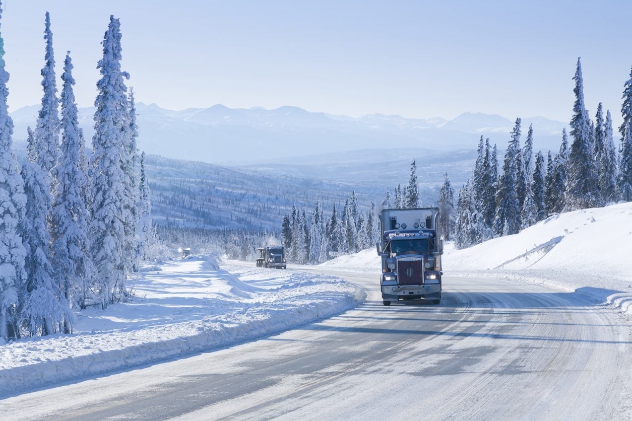 Semi truck on a snow packed highway through forested hills