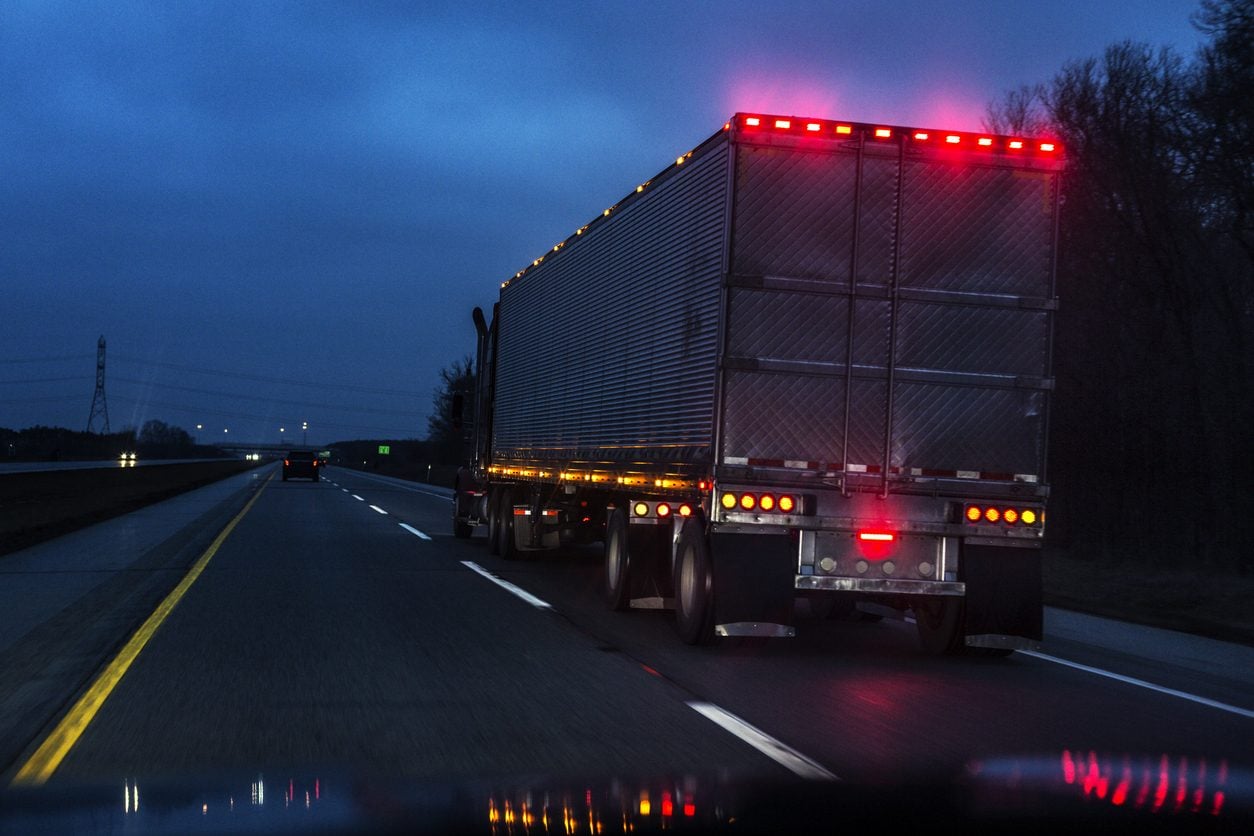 Semi truck parked at a facility after dark